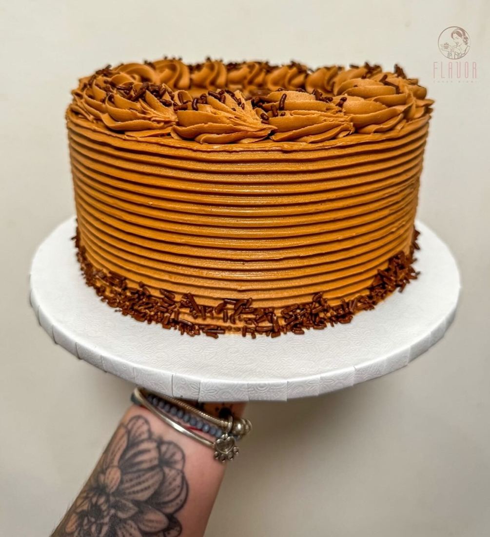 Mano tatuada de Alizon sosteniendo una torta de dulce de leche